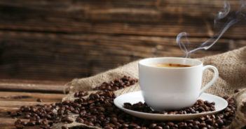 dampfende Kaffeetasse steht auf Kaffeebohnen