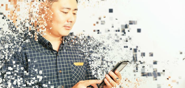 Mensch mit Smartphone in der Hand umgeben von fliegenden Pixeln