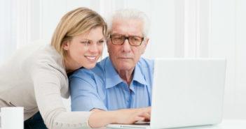 Erwachsene Tochter zeigt Ihrem Vater am Laptop wie etwas funktioniert