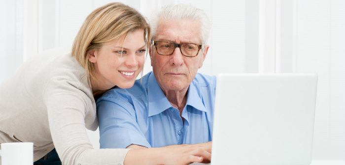 Erwachsene Tochter zeigt Ihrem Vater am Laptop wie etwas funktioniert