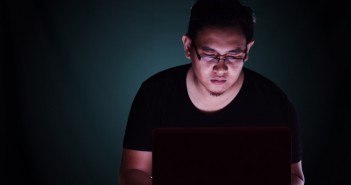 Männlicher Aisate arbeitet an einem Laptop in einem dunklen Raum