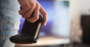 Xbox-Controller in der Hand eines jungen Mannes vor dem Fernseher