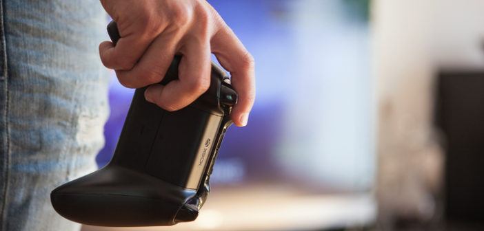 Xbox-Controller in der Hand eines jungen Mannes vor dem Fernseher