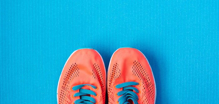 Orange Laufschuhe mit Schnürsenkeln auf blauen Grund