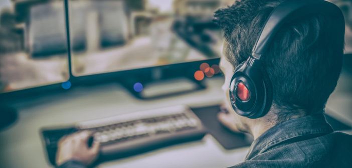 Mann sitzt vor PC-Monitoren und spielt Call of Duty WW2