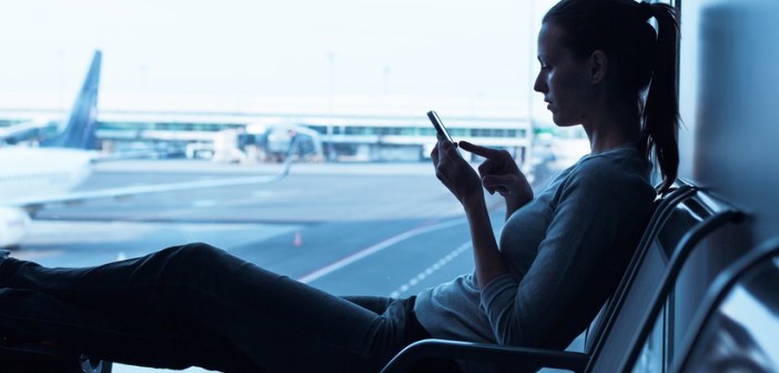 Frau mit Smartphone am Flughafen