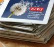 Stapel Zeitungen und ein Tablet mit Nachrichten